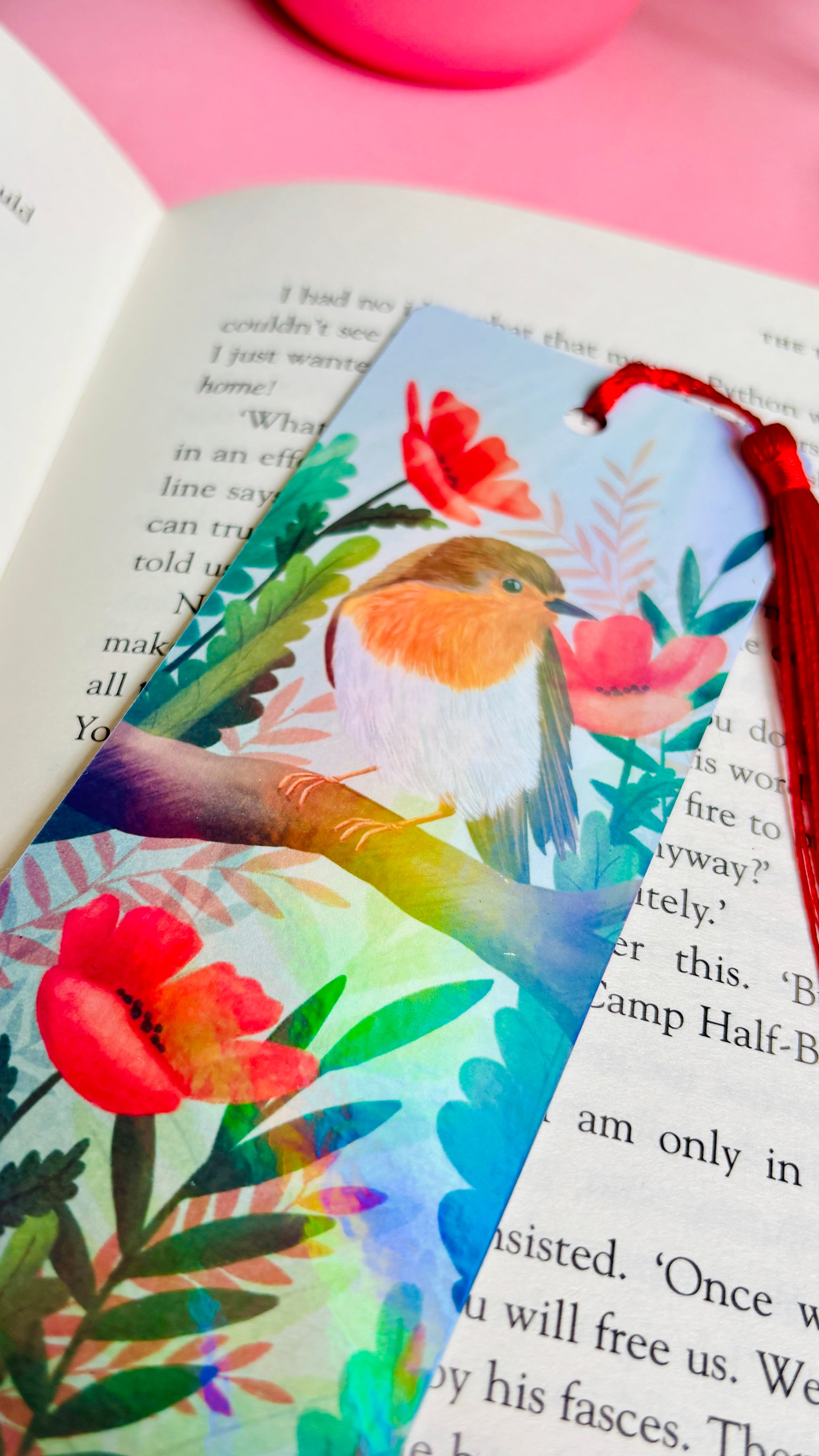 Handmade bookmark with a beautiful hand drawn illustration of a robin sitting among poppies. Finished with a rainbow holographic laminate, rounded corners and a tassel. The symbols of remembrance make this bookmark a thoughtful grief gift or way or remembering lost loved ones.