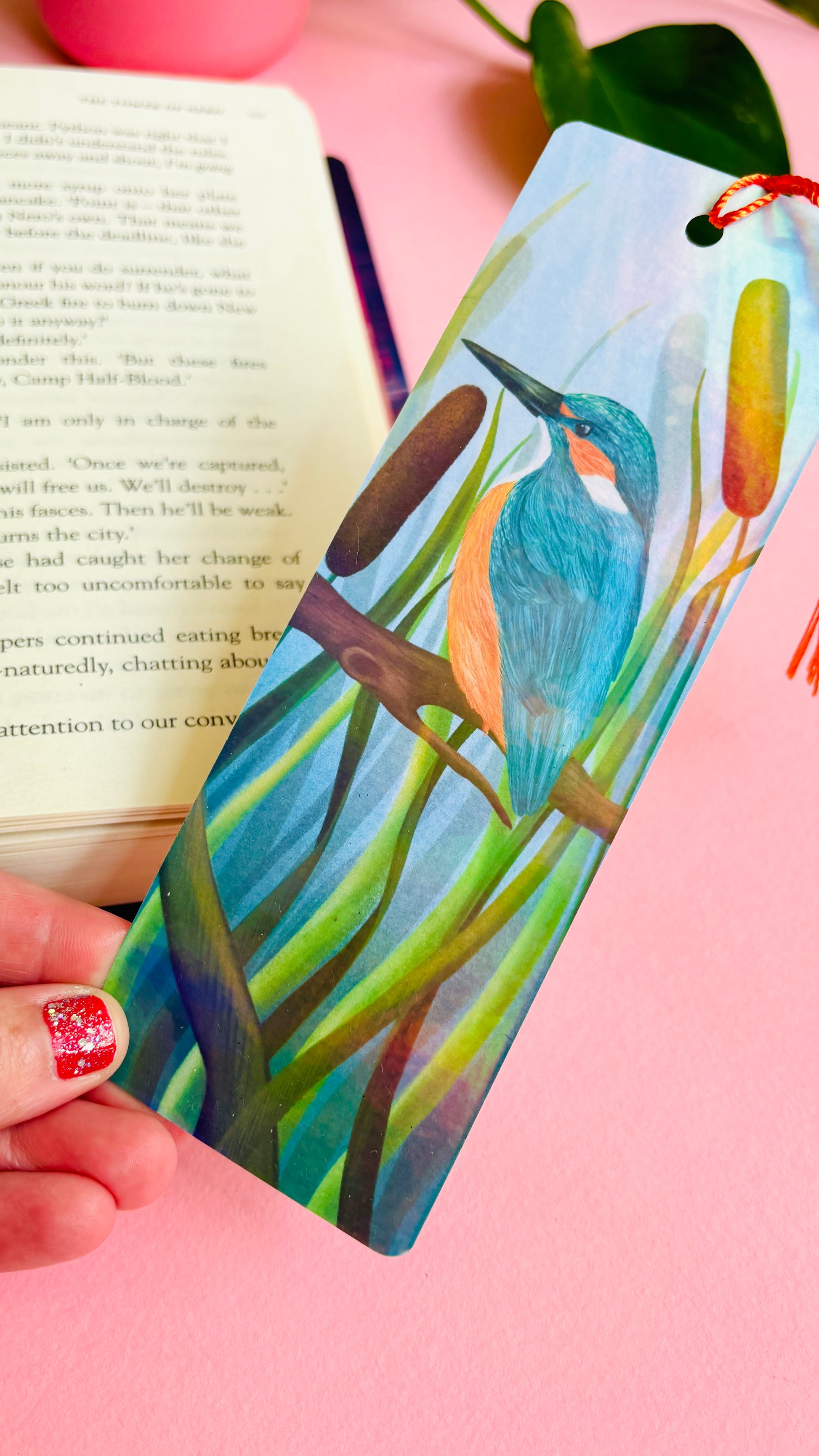 Handmade bookmark with a beautiful illustration of a kingfisher bird in the reads. This holographic bookmark has a rainbow laminate finish, tassel and rounded corners. Ideal for bookish gifts and nature lovers.
