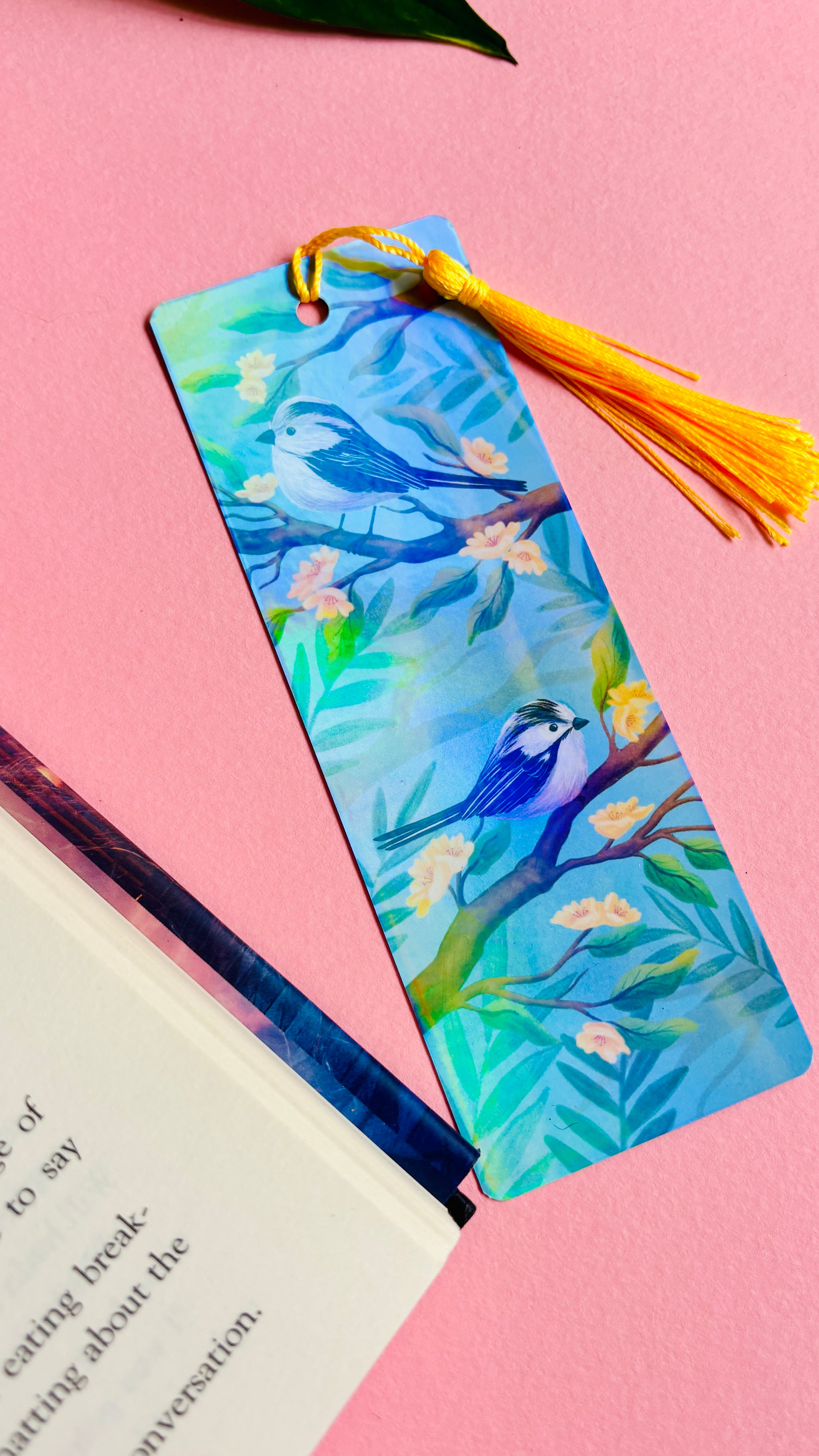Handmade bookmark with illustration of two cute long tailed tits sitting on delicate branches surrounded by yellow flowers. Finished with rainbow holographic laminate, rounded corners and a tassel. Ideal gift for bookish gifts lovers.