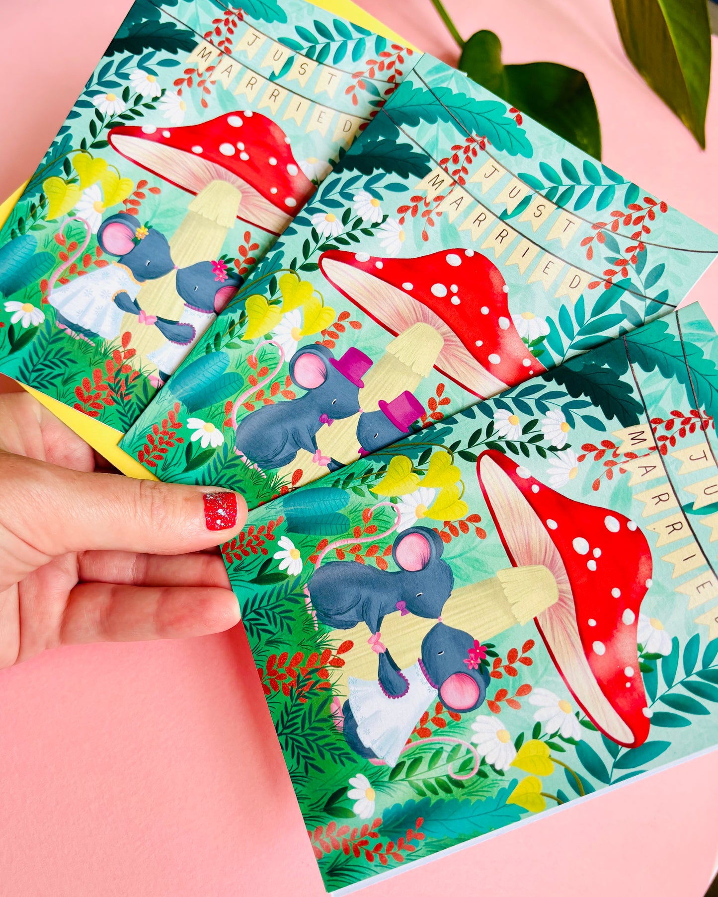 Handmade wedding card with a fantasy forest theme of two mice under a whimsical toadstool in a vibrant woodland setting full of flowers and plants. This handmade card is blank on the inside for your message a d supplied with a yellow envelope