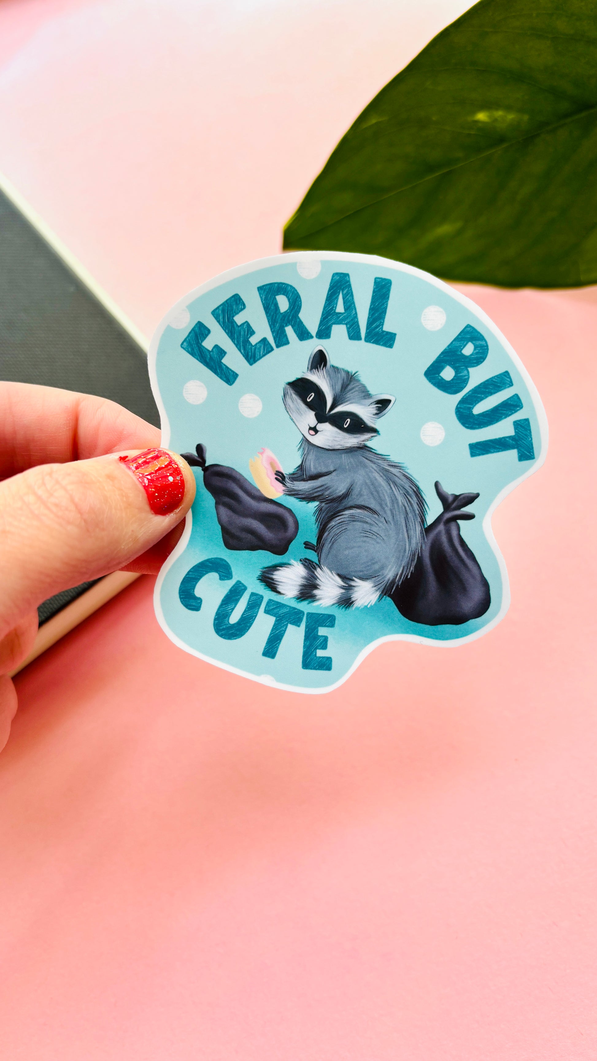 Handmade raccoon vinyl sticker with playful “Feral but Cute” design – perfect for laptops, water bottles, and scrapbooks.