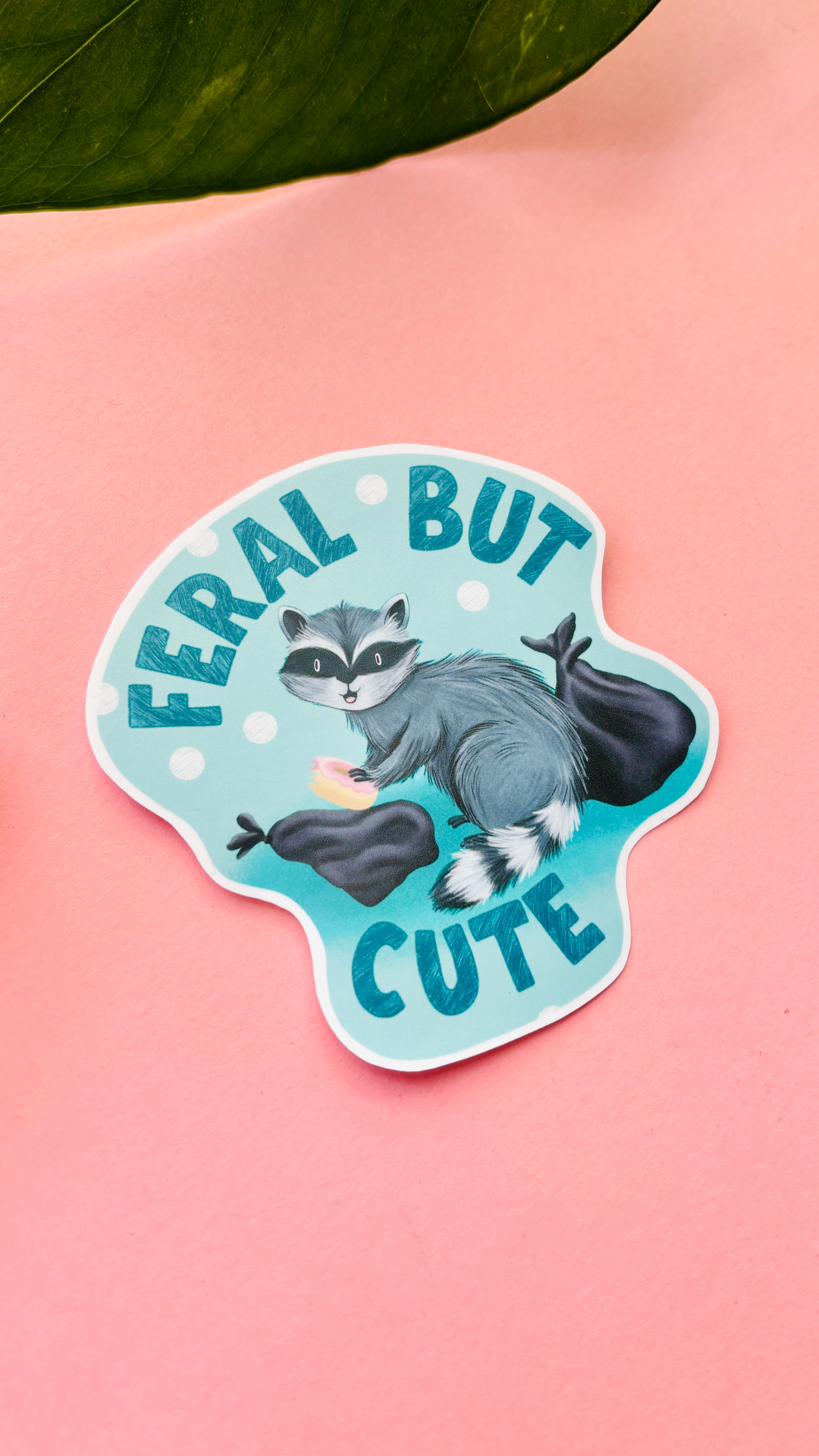 Handmade raccoon vinyl sticker with playful “Feral but Cute” design – perfect for laptops, water bottles, and scrapbooks.