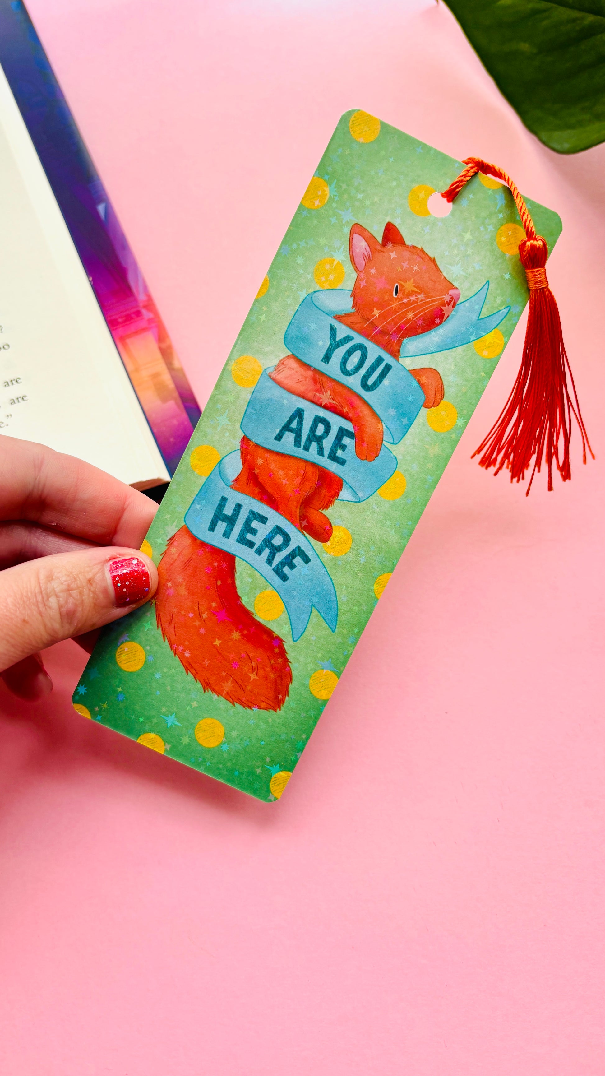 Handmade ginger cat Gift bookmark with holographic rainbow finish, orange tassel, retro “You are here” banner, and green polka dot background, perfect for cat lovers and bookworms.