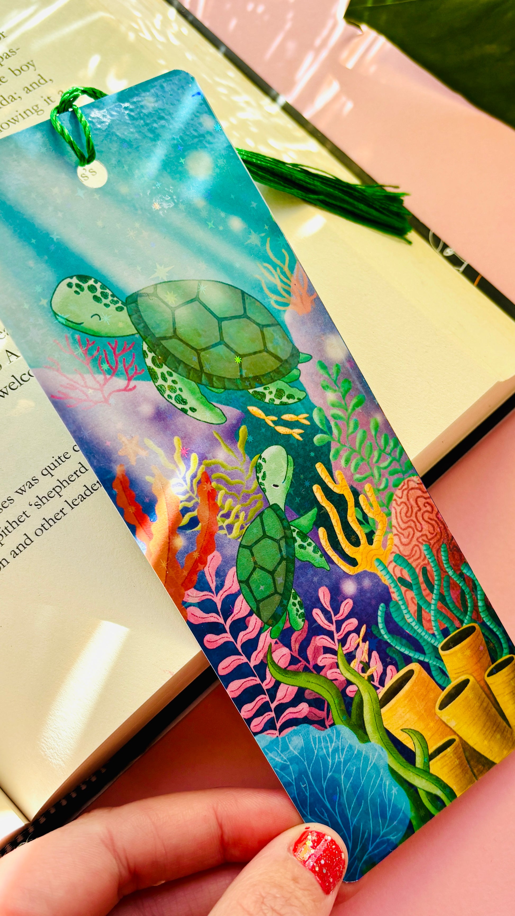 Ocean-inspired bookmark featuring two cute sea turtles swimming through a colorful coral reef, double-sided with rainbow holographic laminate and green tassel, perfect for readers and marine life fans.