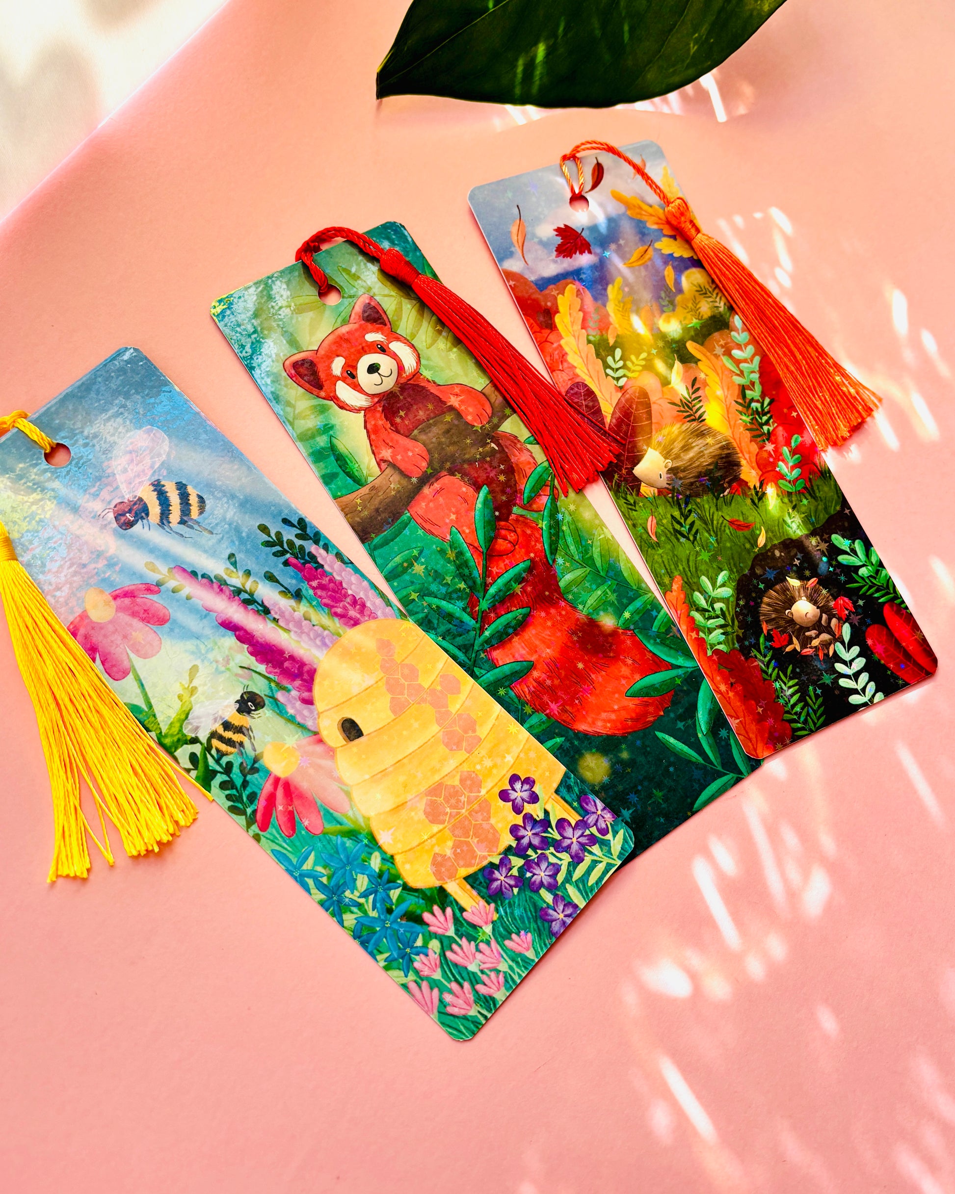 Cute red panda bookmark featuring a whimsical illustration, rainbow holographic laminate, and green tassel, perfect for animal lovers and avid readers.