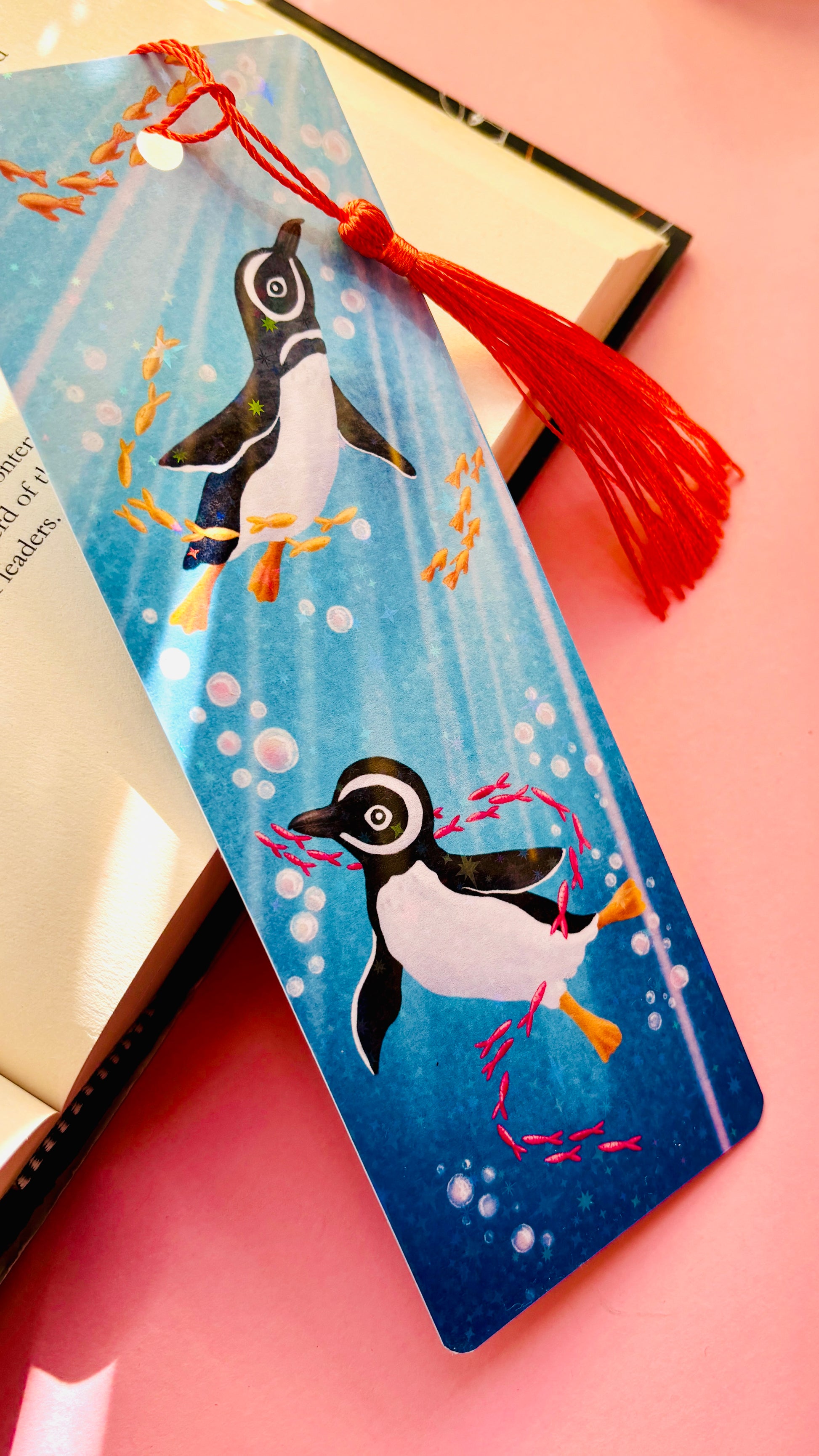 Colorful handmade penguin bookmark with ocean scene and holographic shimmer, finished with a coordinating tassel, perfect for penguin lovers and bookworms.