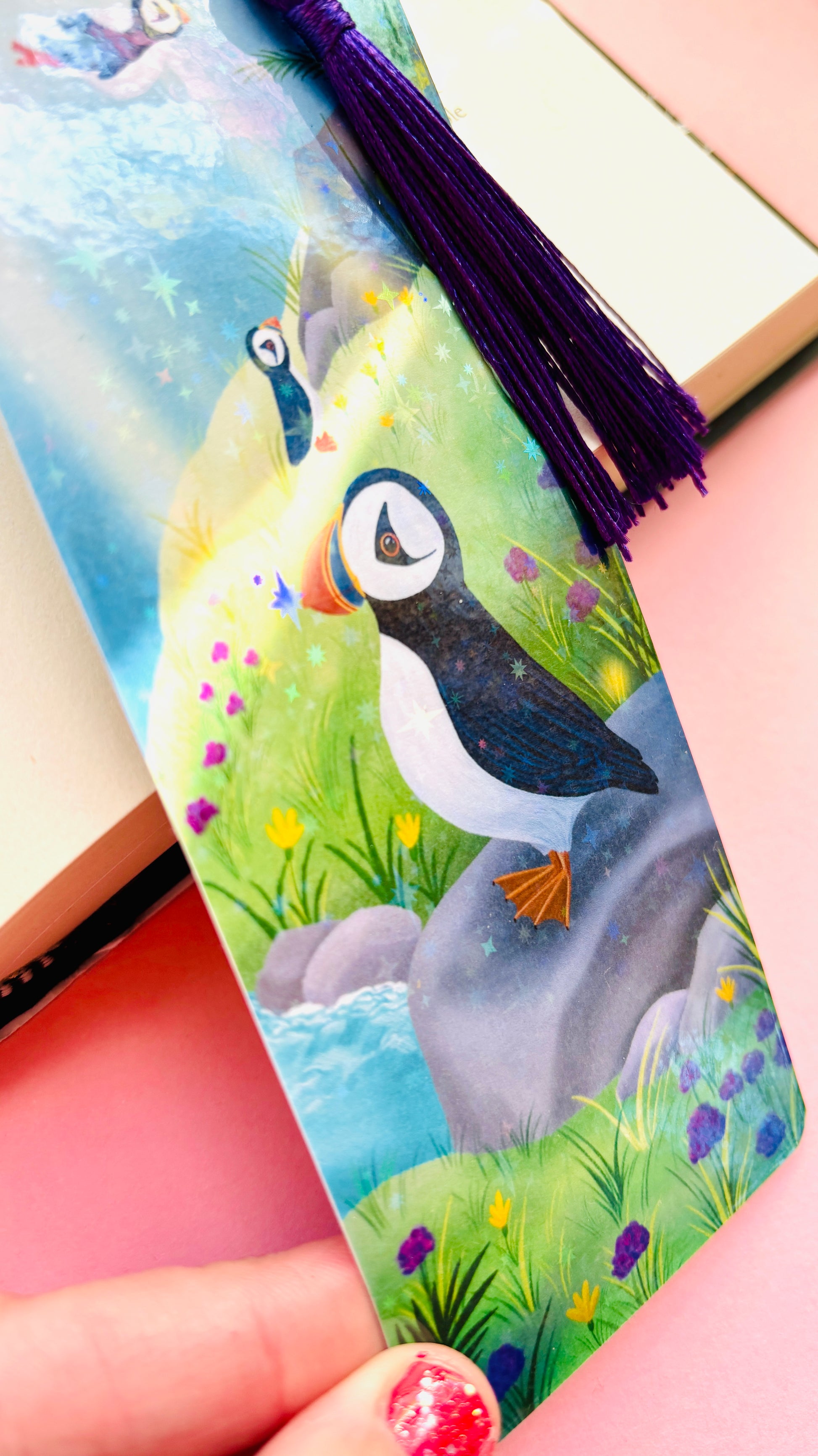 Colorful holographic puffin bookmark with seaside background and tassel, handmade FSC-certified paper accessory for puffin fans, bookworms, and journaling enthusiasts.