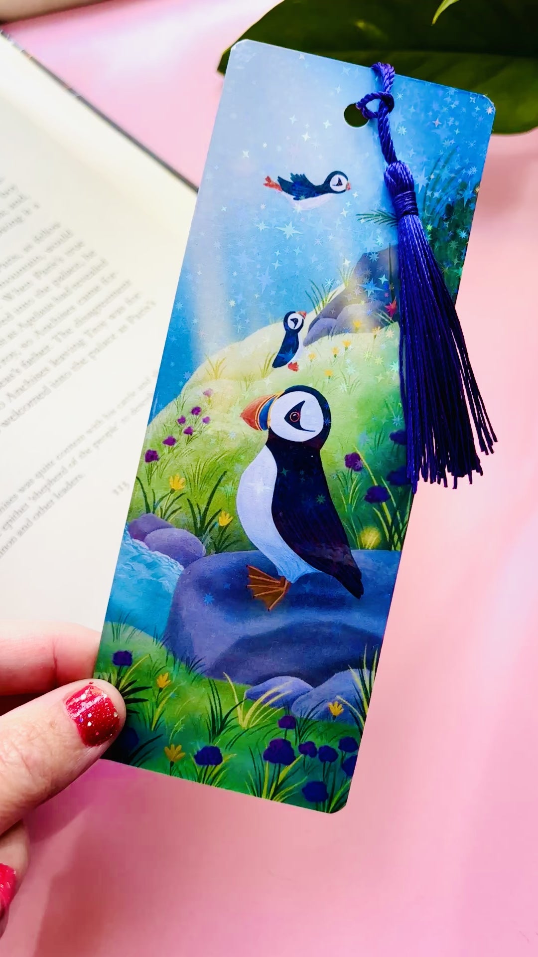 Handmade puffin bookmark with rainbow holographic finish, featuring a cute puffin on a colorful coastal seaside scene, FSC-certified paper, and coordinating tassel, perfect for book lovers and bird enthusiasts.