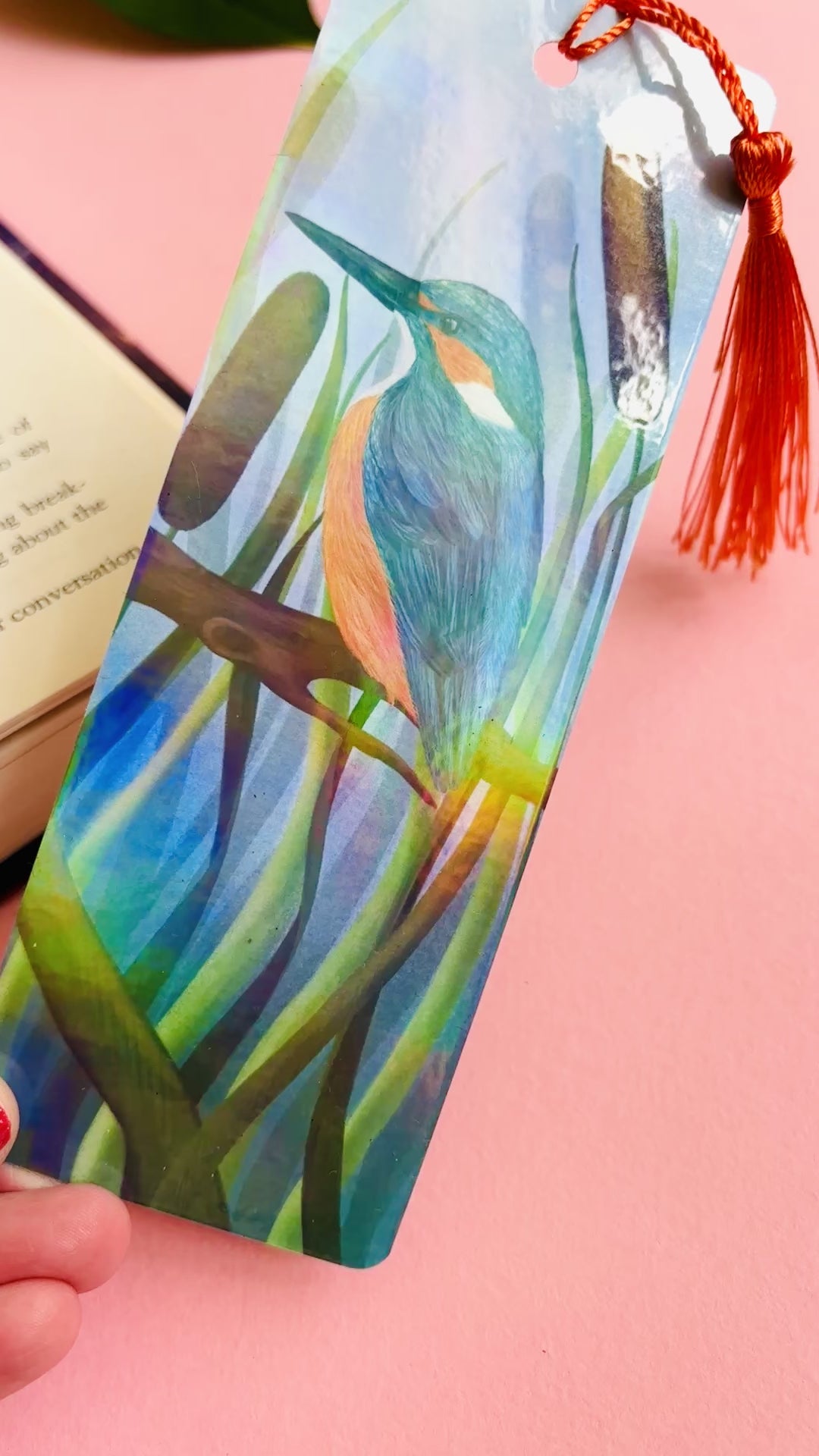 Handmade bookmark with a beautiful illustration of a kingfisher bird in the reads. This holographic bookmark has a rainbow laminate finish, tassel and rounded corners. Ideal for bookish gifts and nature lovers.