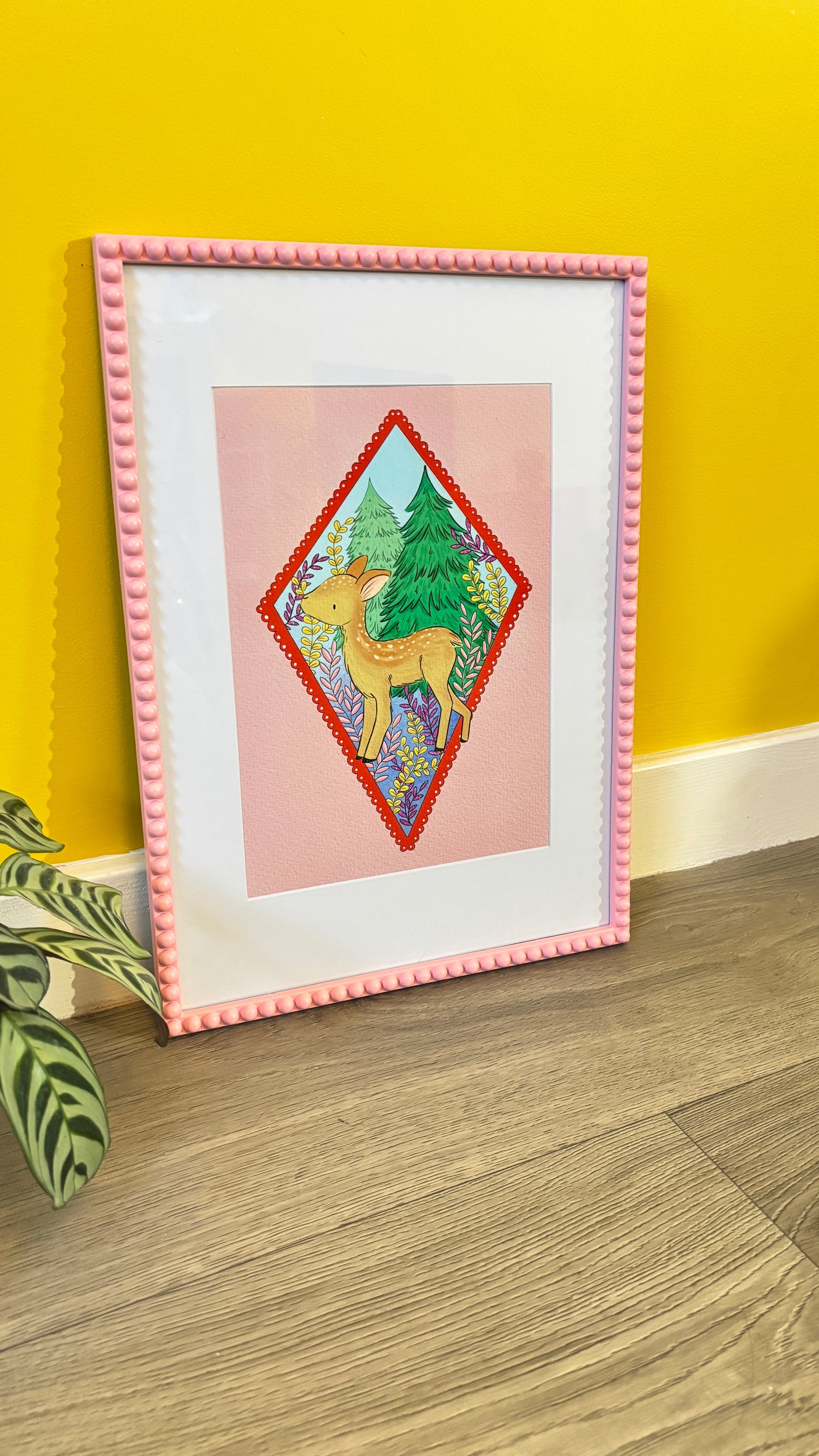 Art print of a baby deer on a pink background with colourful trees and plants