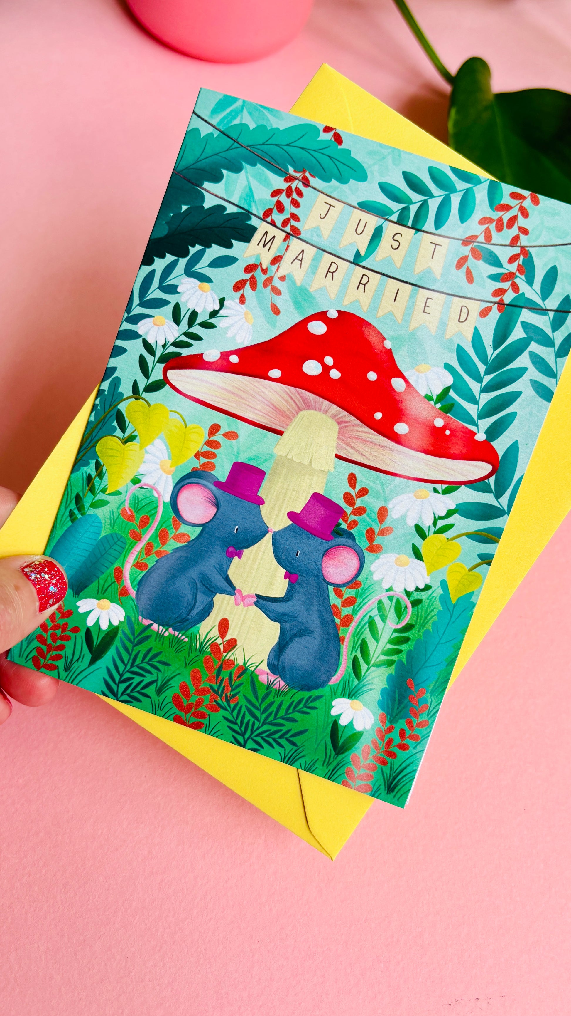 Cute gay wedding card of two mice under a whimsical toadstool in a vibrant woodland setting full of flowers and plants. This handmade card is blank on the inside for your message a d supplied with a yellow envelope 