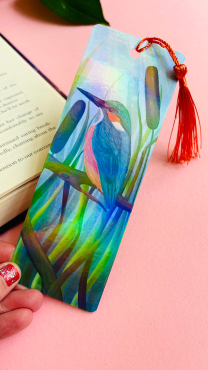 Handmade bookmark with a beautiful illustration of a kingfisher bird in the reads. This holographic bookmark has a rainbow laminate finish, tassel and rounded corners. Ideal for bookish gifts and nature lovers. 