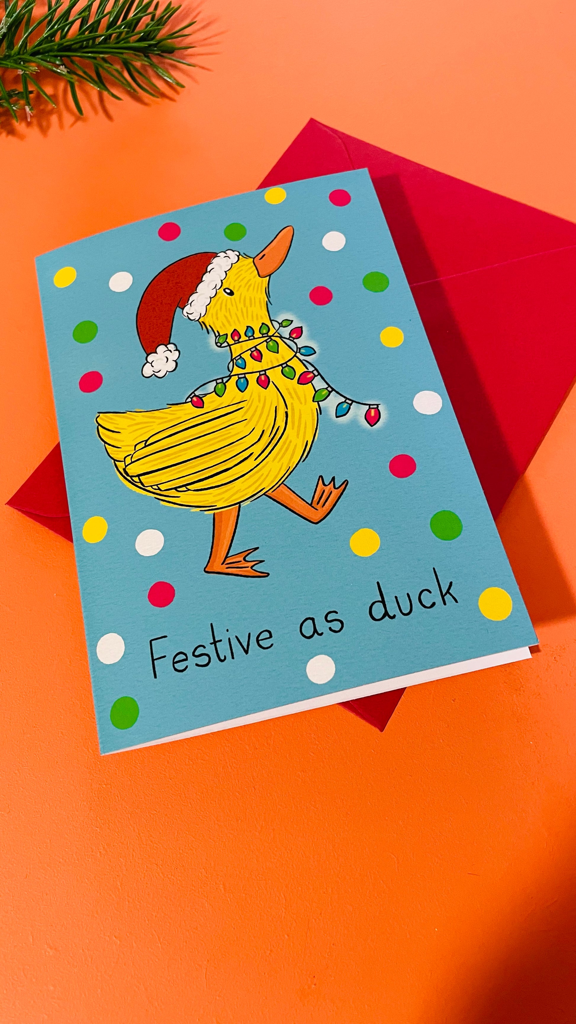 Duck Christmas card reading festive as duck under a duck in a Santa hat wrapped in fairy lights