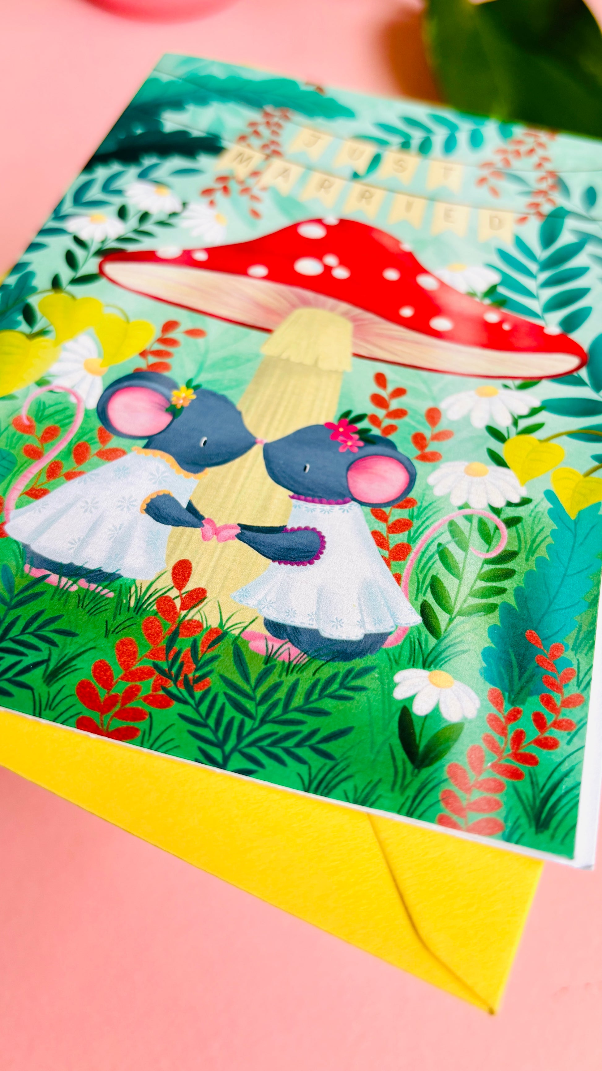 Handmade lesbian wedding card of two mice under a whimsical toadstool in a vibrant woodland setting full of flowers and plants. This handmade card is blank on the inside for your message a d supplied with a yellow envelope 