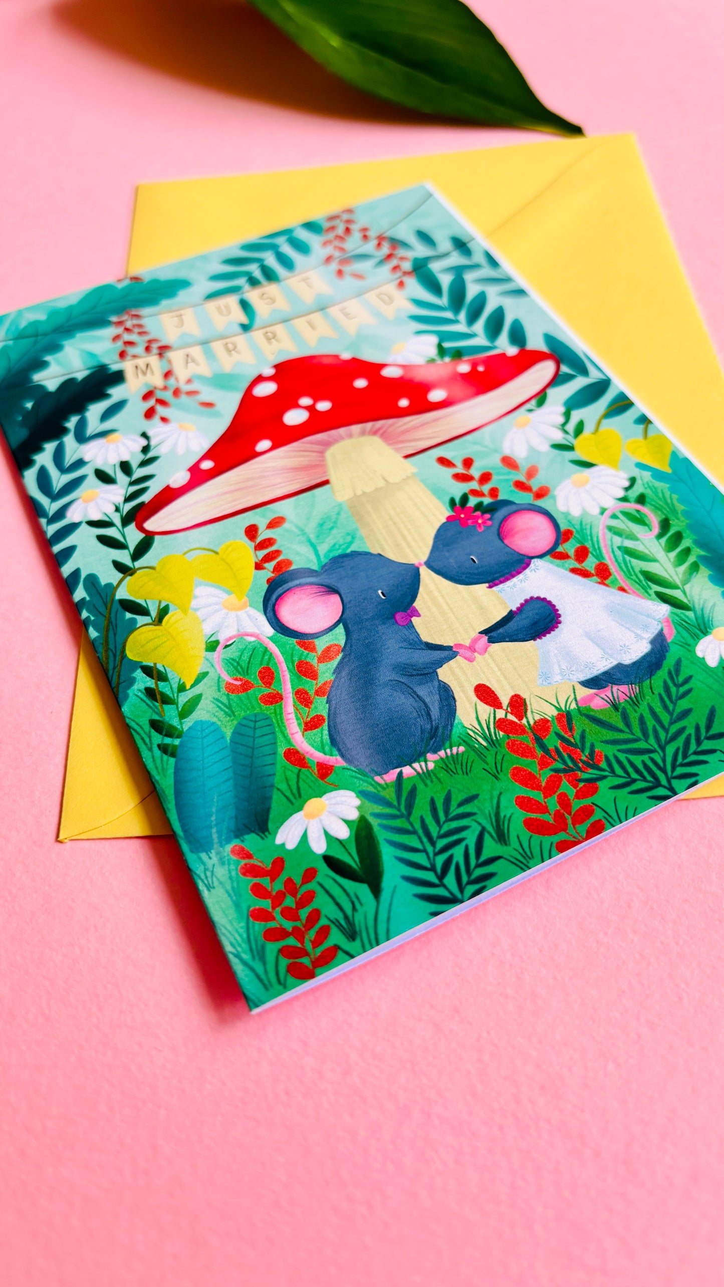 Handmade wedding card with a fantasy forest theme of two mice under a whimsical toadstool in a vibrant woodland setting full of flowers and plants. This handmade card is blank on the inside for your message a d supplied with a yellow envelope 