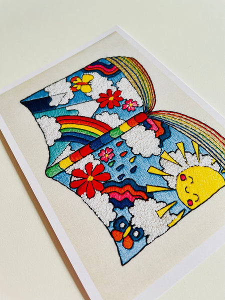 Hand embroidered art print of a book made from rainbows, sunshine and flowers.