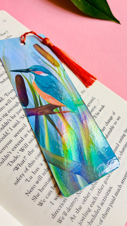 Handmade bookmark with a beautiful illustration of a kingfisher bird in the reads. This holographic bookmark has a rainbow laminate finish, tassel and rounded corners. Ideal for bookish gifts and nature lovers. 
