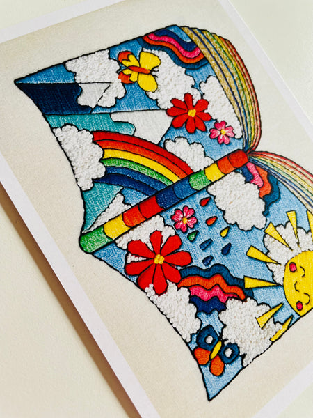 Hand embroidered art print of a book made from rainbows, sunshine and flowers.