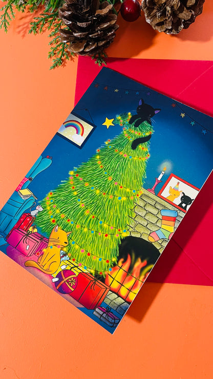 Illustrated card of two cats by a fire and a glowing, twinkly Christmas tree