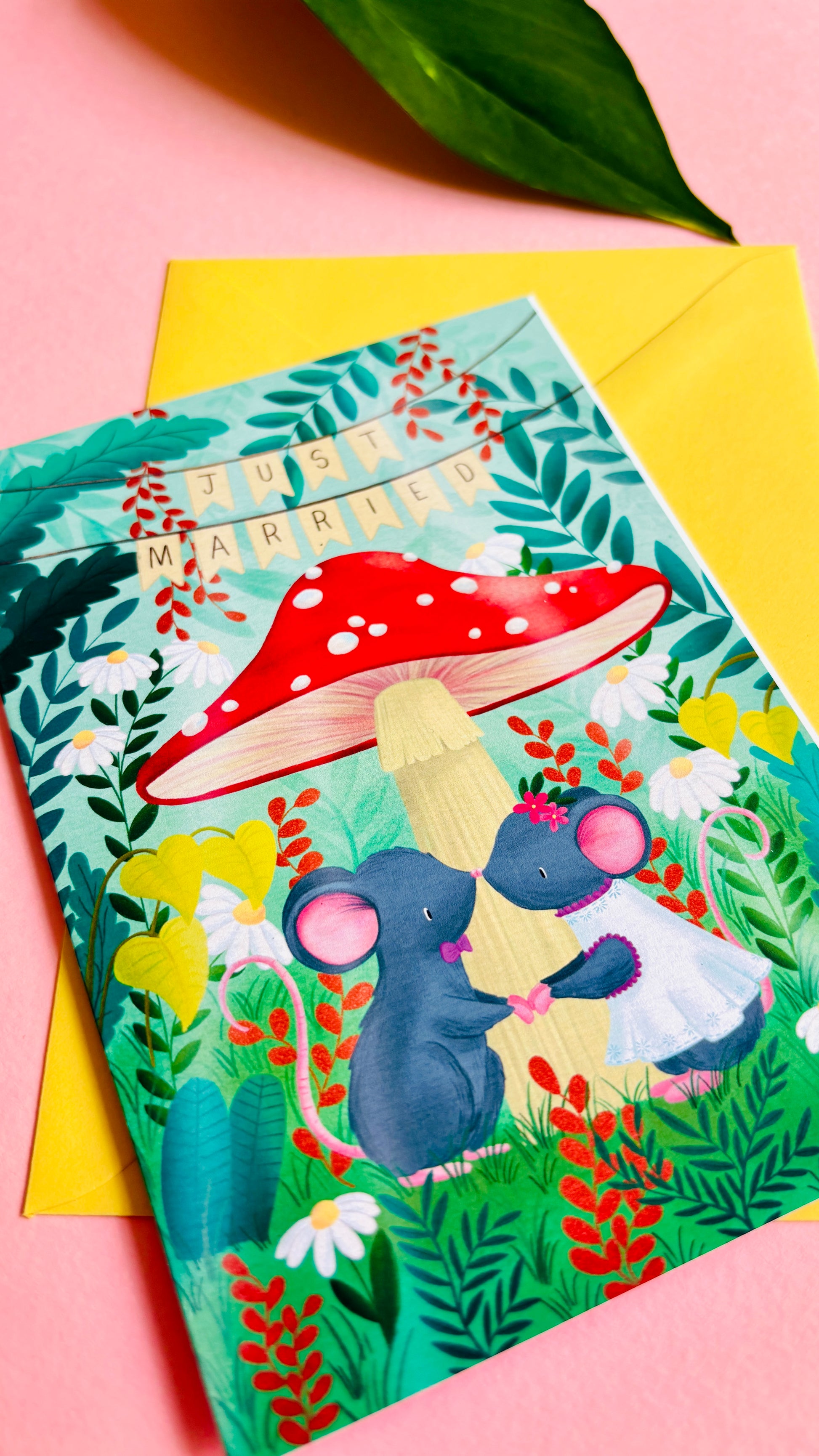 Handmade wedding card with a fantasy forest theme of two mice under a whimsical toadstool in a vibrant woodland setting full of flowers and plants. This handmade card is blank on the inside for your message a d supplied with a yellow envelope 