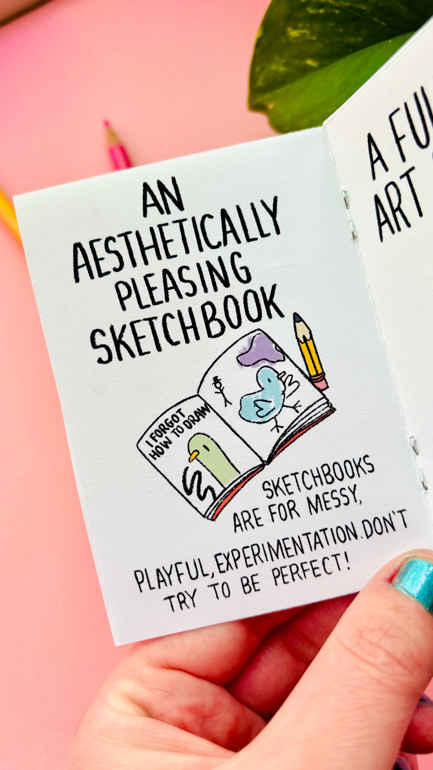 Hand holding a small illustrated advice zine for artists, showing scale and cover design