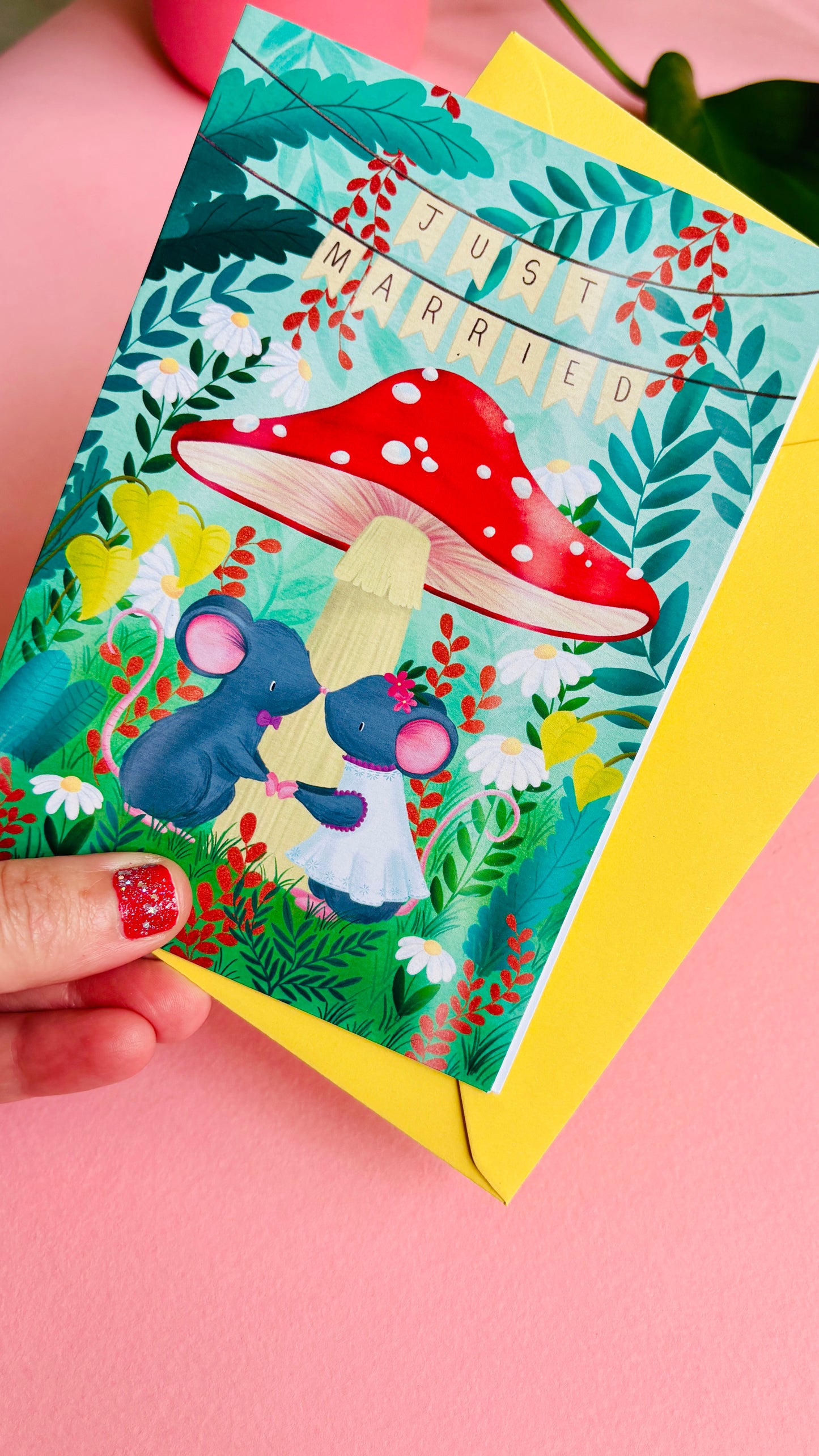 Handmade wedding card with a fantasy forest theme of two mice under a whimsical toadstool in a vibrant woodland setting full of flowers and plants. This handmade card is blank on the inside for your message a d supplied with a yellow envelope 