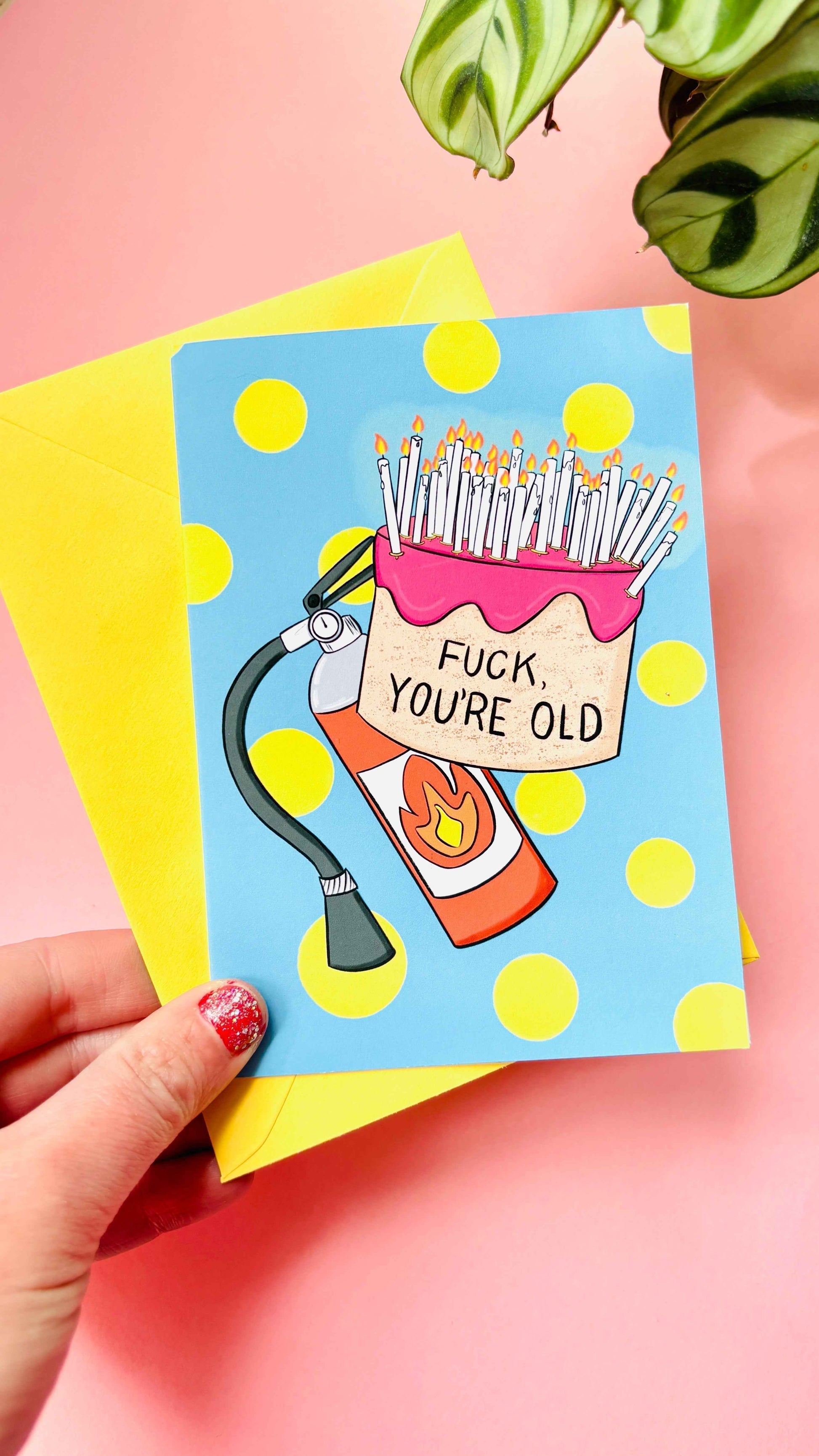 This handmade Sweary rude birthday card features a cake overflowing with candles and pre-cautionary fire extinguisher under the funny text “fuck you’re old” against a blue background with yellow polkadots 