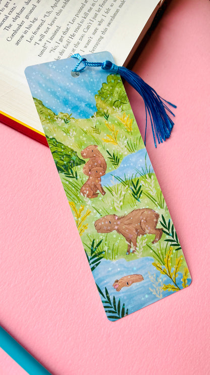Illustrated bookmark with a capybara design with a rainbow holographic bookmark. 