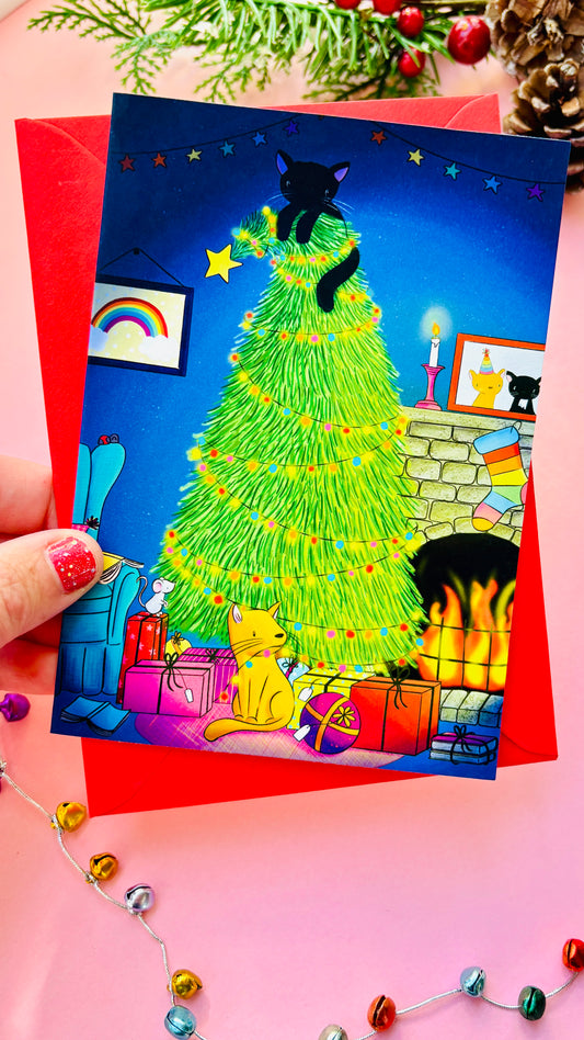 Handmade Christmas card with two playful cats by a decorated tree and fireplace, perfect festive greeting for cat lovers.