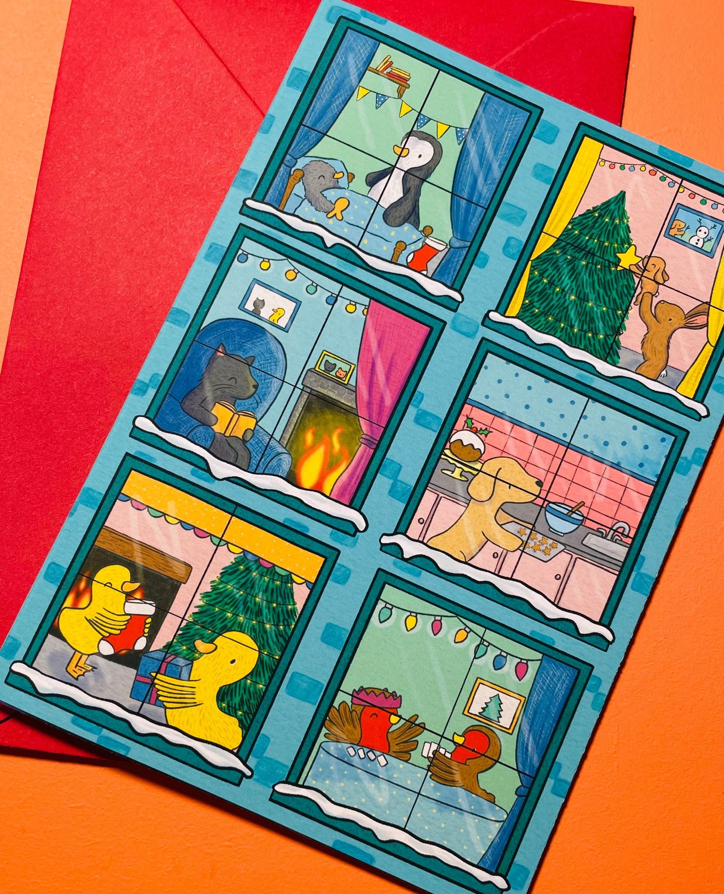 This adorable Christmas card shows a blue building in every window there is a different animal in a Christmas scene.