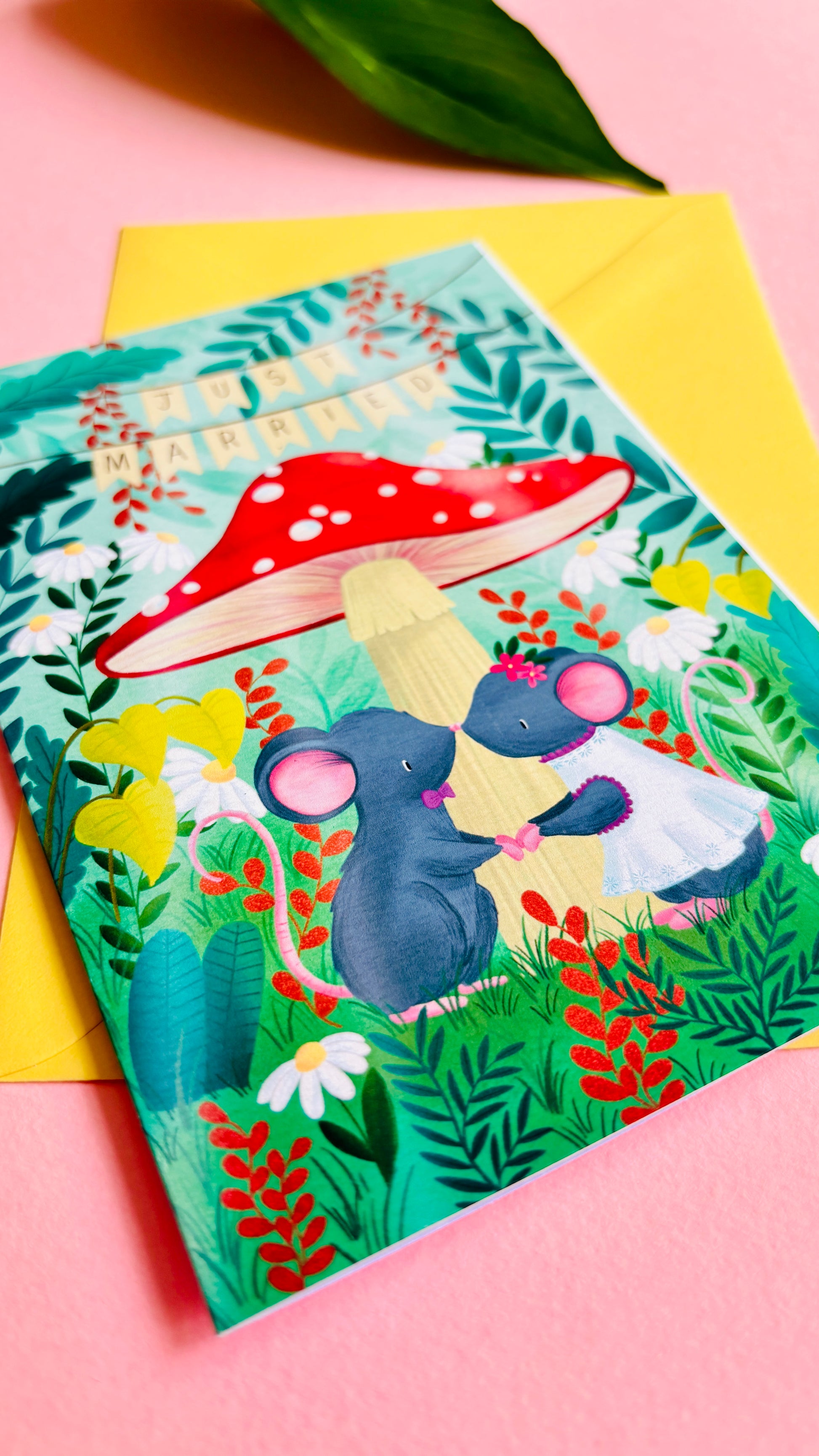 Handmade wedding card with a fantasy forest theme of two mice under a whimsical toadstool in a vibrant woodland setting full of flowers and plants. This handmade card is blank on the inside for your message a d supplied with a yellow envelope 
