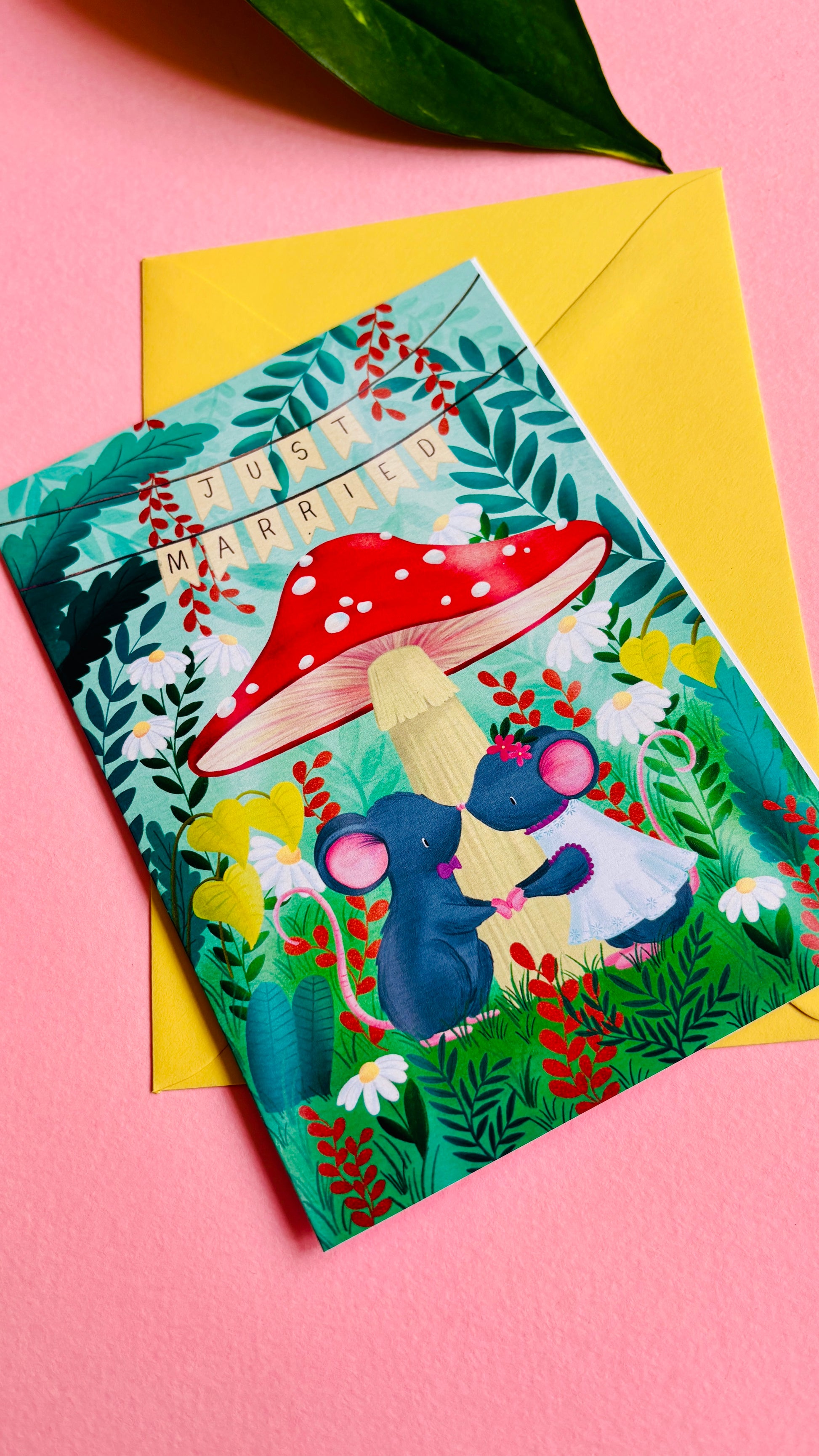 Handmade wedding card with a fantasy forest theme of two mice under a whimsical toadstool in a vibrant woodland setting full of flowers and plants. This handmade card is blank on the inside for your message a d supplied with a yellow envelope 