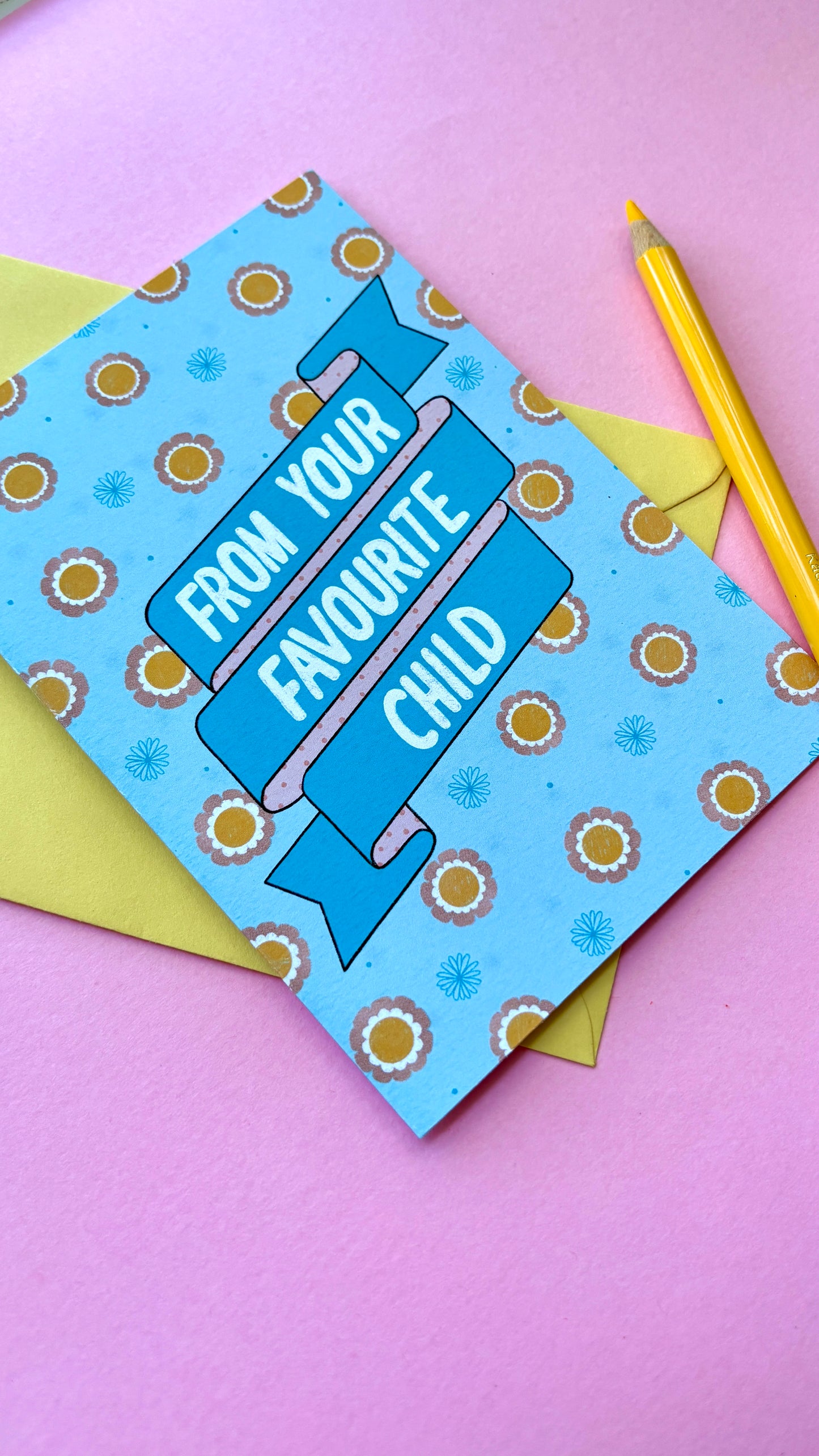 A funny handmade greetings card for mum or dad and reads “from your favourite child” on a blue and pink banner against a colourful retro feel floral background. Supplied with a yellow envelope.