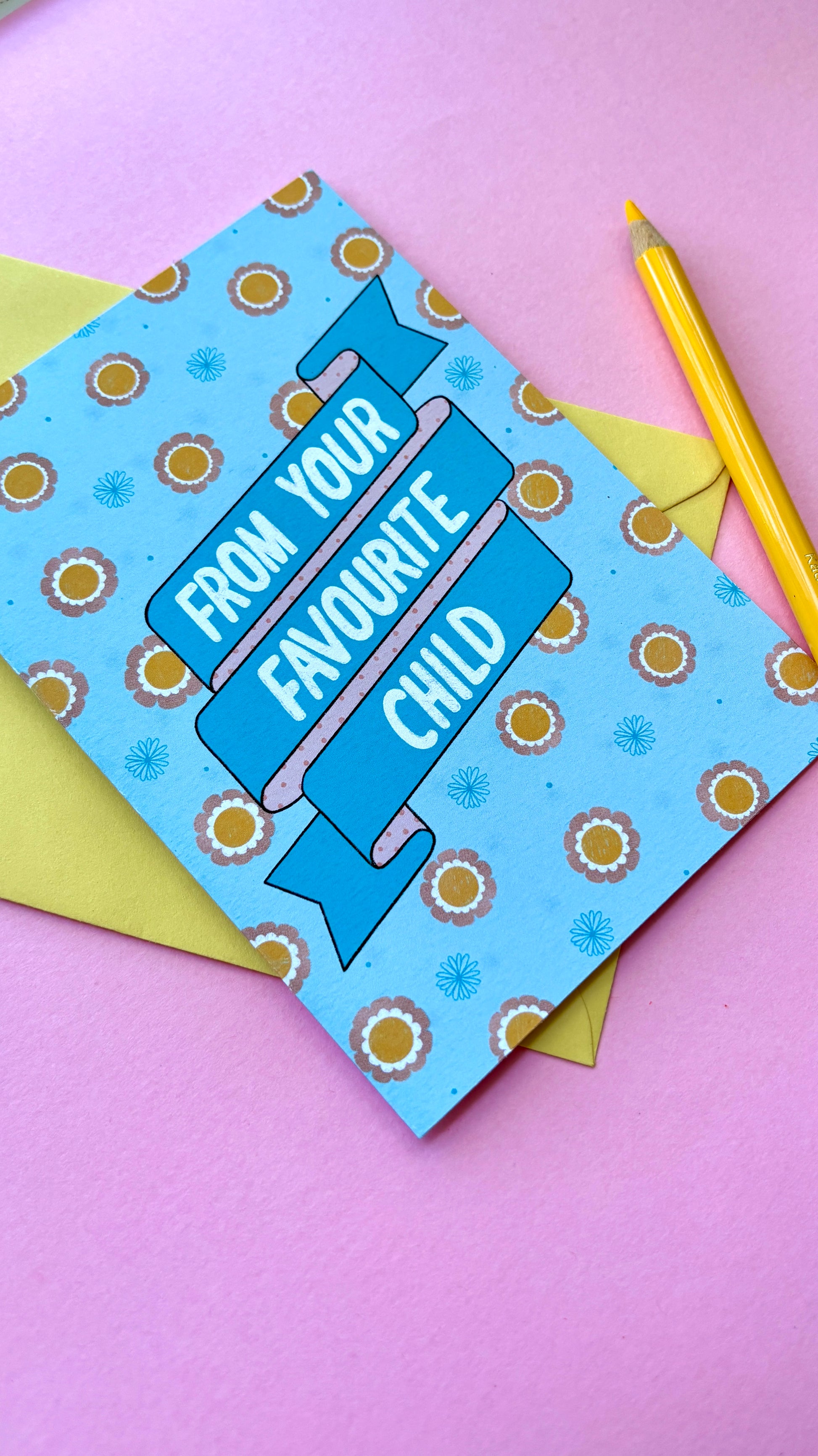 A funny handmade greetings card for mum or dad and reads “from your favourite child” on a blue and pink banner against a colourful retro feel floral background. Supplied with a yellow envelope.