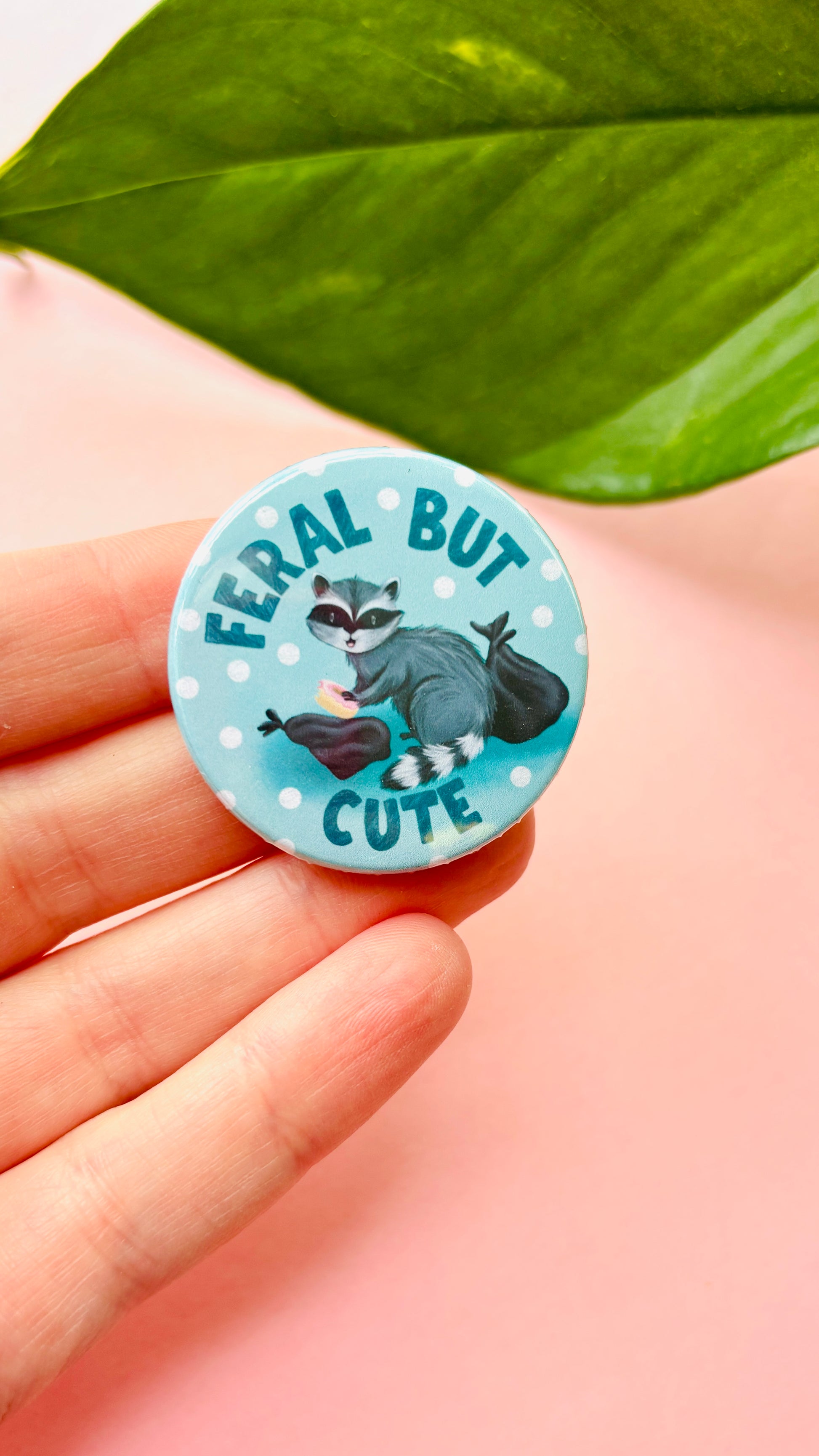 Handmade “Feral but Cute” raccoon badge or magnet, illustrated in a cute cartoon style – a fun gift for animal lovers, wildlife fans, and quirky accessory collectors.