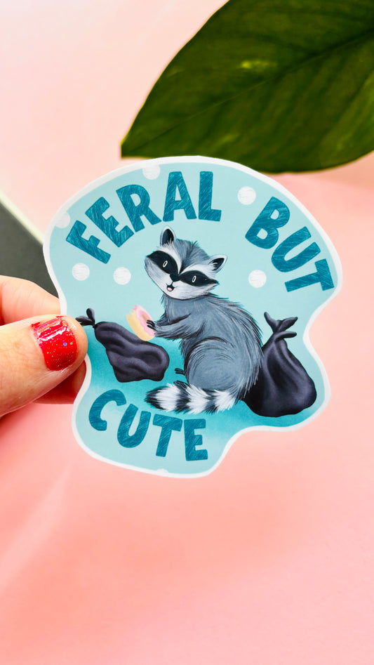 Hand-illustrated “Feral but Cute” raccoon vinyl sticker – waterproof, durable, and handmade in the UK. Perfect for laptops, water bottles, notebooks, and planners.
