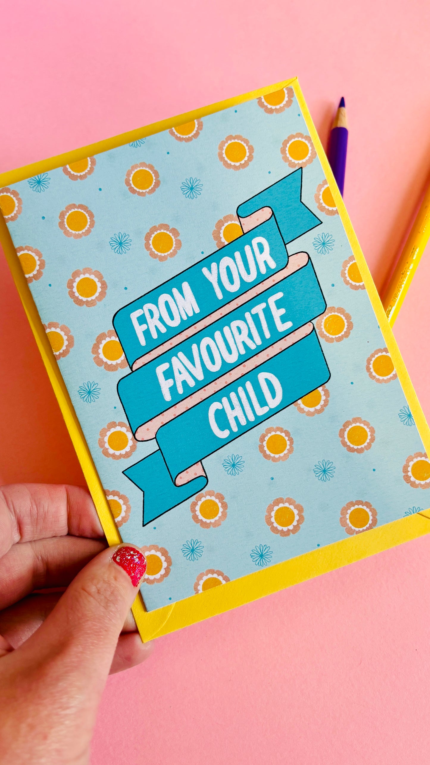 A funny handmade greetings card for mum or dad and reads “from your favourite child” on a blue and pink banner against a colourful retro feel floral background. Supplied with a yellow envelope.