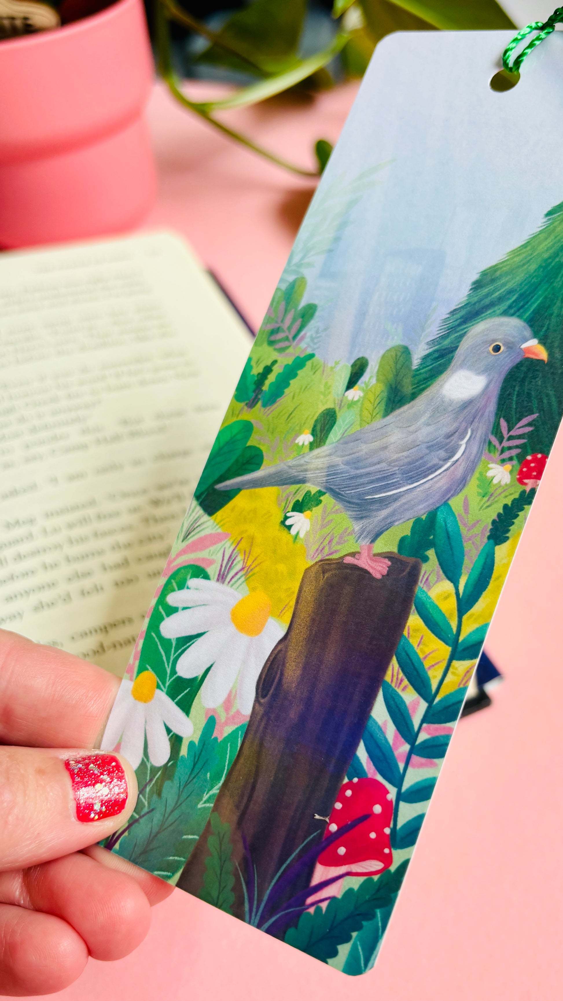 Handmade bookmark with cute pigeon art. This holographic bookmark features an adorable wood pigeon sitting on a mossy tree stump surrounded by colourful plants and flowers with a subtle cityscape in the background. Finished with a tassel, rounded corners and rainbow holographic laminate it makes a great gift for pigeon lovers and bookish besties. 