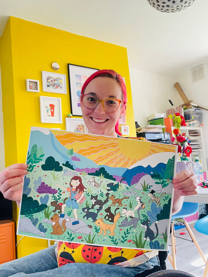 Colourful illustration of a girl and a group of cats adventuring through a cololourful wild landscape held by a white female with red hair and colouful glasses 