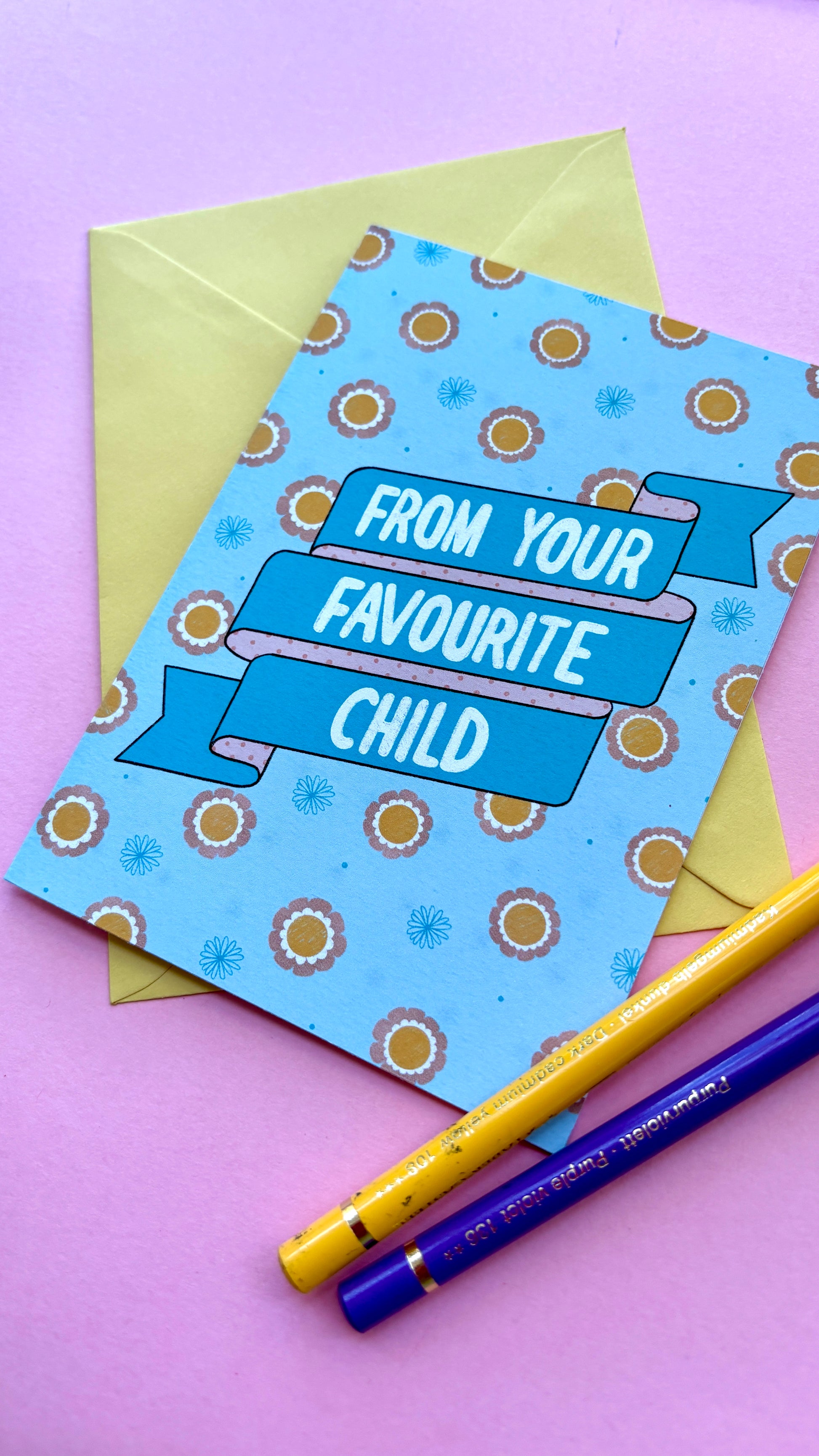 A funny handmade greetings card for mum or dad and reads “from your favourite child” on a blue and pink banner against a colourful retro feel floral background. Supplied with a yellow envelope.