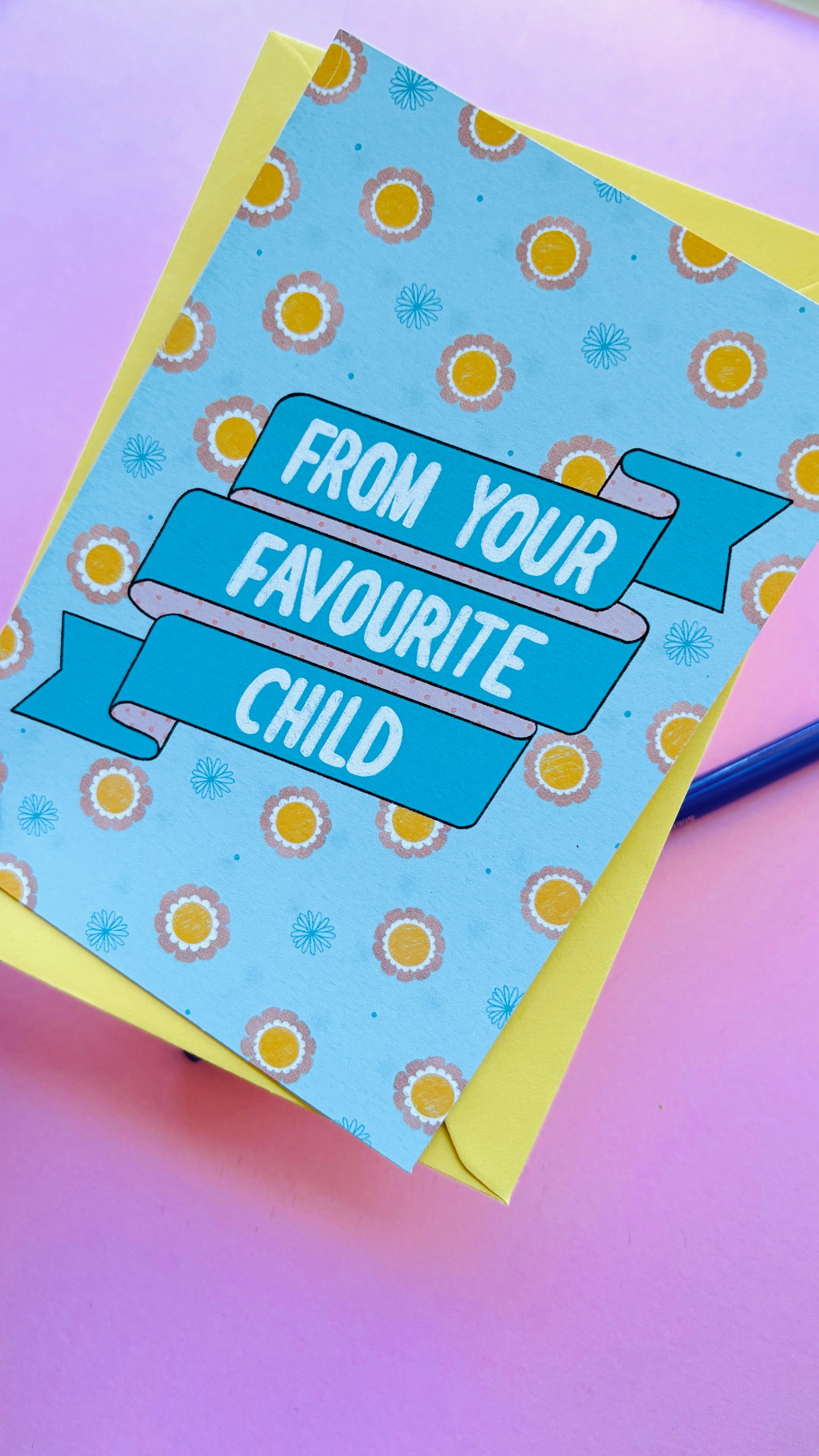 A funny handmade greetings card for mum or dad and reads “from your favourite child” on a blue and pink banner against a colourful retro feel floral background. Supplied with a yellow envelope.