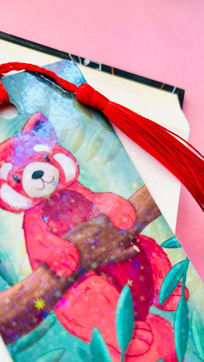 Cute red panda bookmark featuring a whimsical illustration, rainbow holographic laminate, and green tassel, perfect for animal lovers and avid readers.