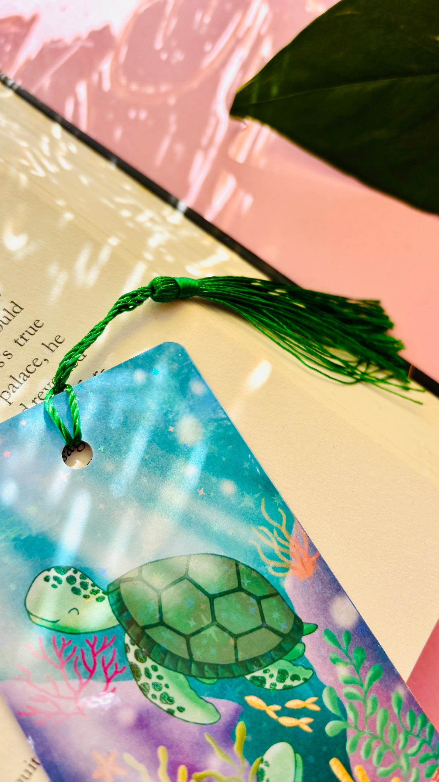 Double-sided turtle gift bookmark showing two hand-drawn sea turtles swimming in a coral reef, finished with rainbow holographic laminate and green tassel for marking pages.