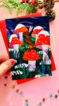 Handmade woodland Christmas card with a brown bunny on a red toadstool under a magical winter sky, perfect for nature lovers.