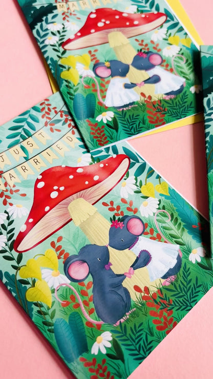 Cute gay wedding card of two mice under a whimsical toadstool in a vibrant woodland setting full of flowers and plants. This handmade card is blank on the inside for your message a d supplied with a yellow envelope 