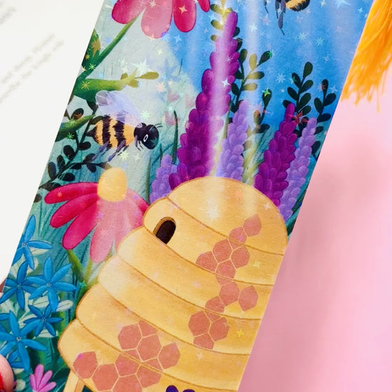 Handmade bee and wildflower bookmark with rainbow holographic finish, featuring playful bees and a colourful meadow, perfect for book lovers and nature enthusiasts