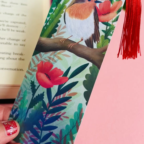 Handmade bookmark with a beautiful hand drawn illustration of a robin sitting among poppies. Finished with a rainbow holographic laminate, rounded corners and a tassel. The symbols of remembrance make this bookmark a thoughtful grief gift or way or remembering lost loved ones. 