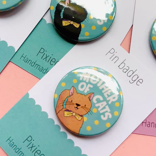 Handmade cat gift pin badge or fridge magnet. This cute accessory reads ‘mother of cats’ and you can choose from four different cat designs; brown tabby cat, orange/ginger cat, black cat, black and white cat. The hand drawn illustration is turned into a pin badge or magnet and presented on a colourful backing card ready for gifting. Great for stocking fillers.