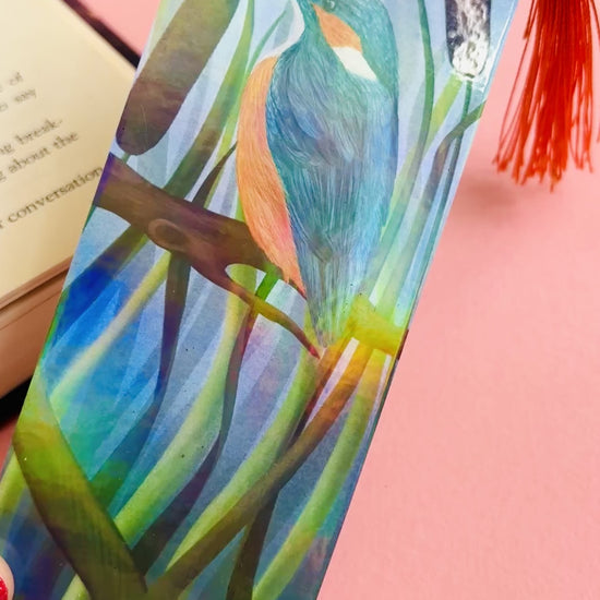 Handmade bookmark with a beautiful illustration of a kingfisher bird in the reads. This holographic bookmark has a rainbow laminate finish, tassel and rounded corners. Ideal for bookish gifts and nature lovers. 