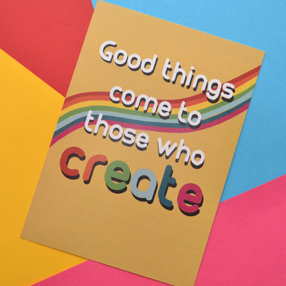 Good things come to those who create in white and rainbow colours on a yellow and rainbow background